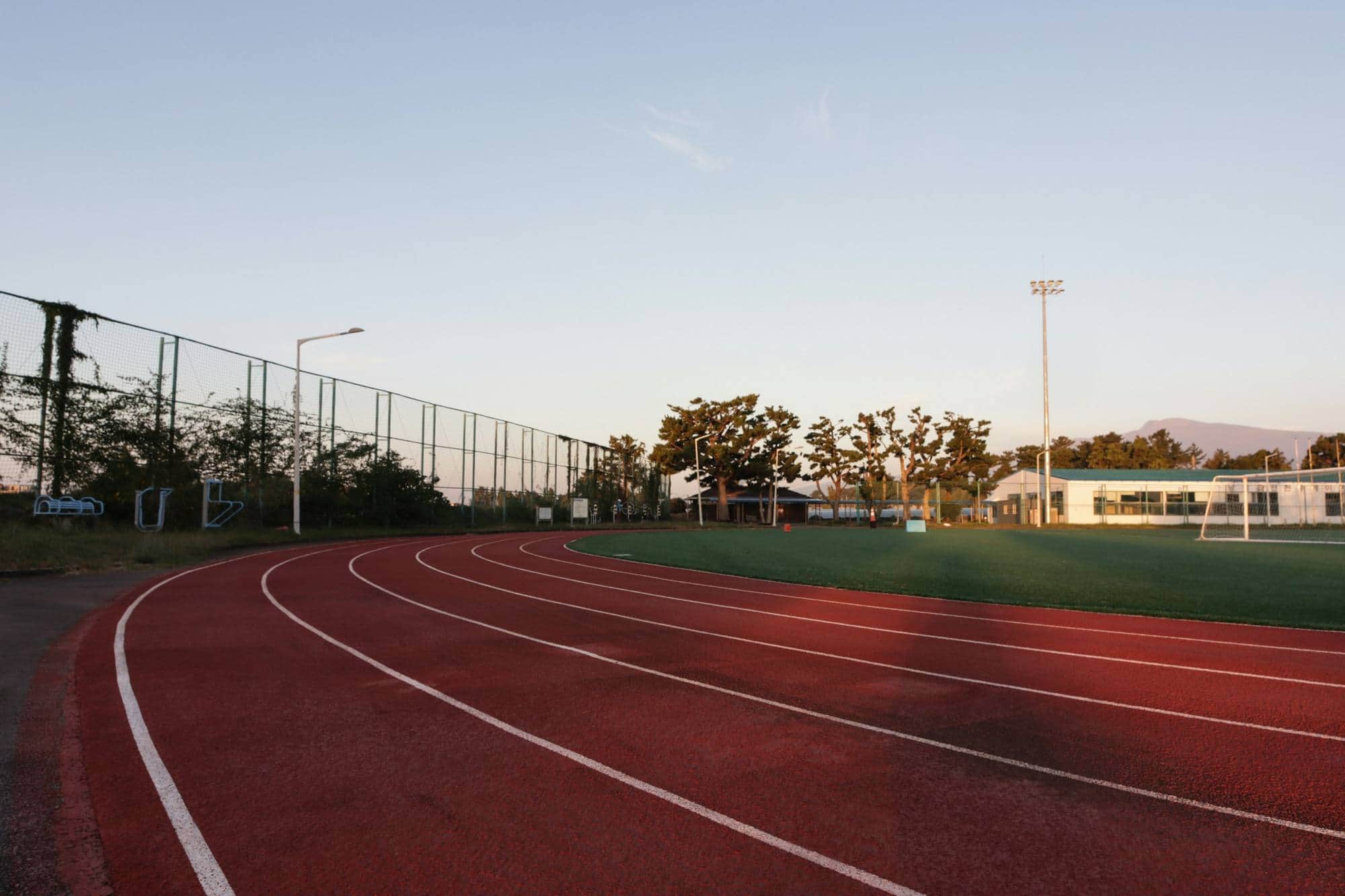 An empty running track curving away under a dusk sky